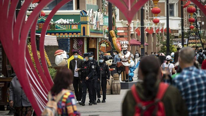 A squad of police officers wearing protective masks patrol the Xinjiang International Grand Bazaar in Urumqi, Xinjiang province, China | Bloomberg