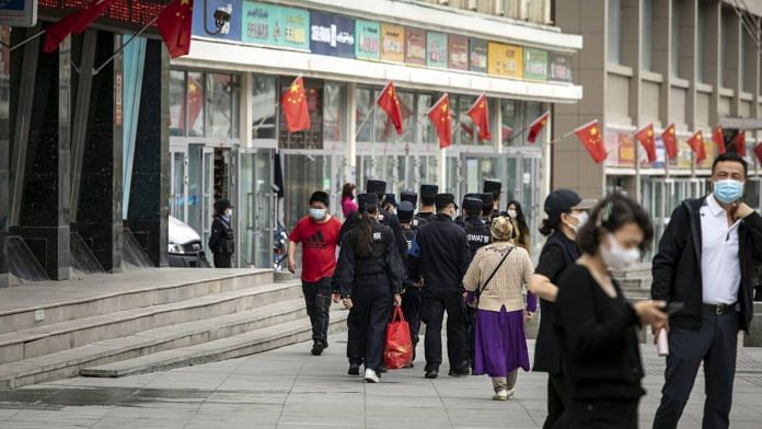 People wear protective masks as they walk through the Xinjiang International Grand Bazaar in Urumqi, Xinjiang province, China, in May 2021 | Bloomberg