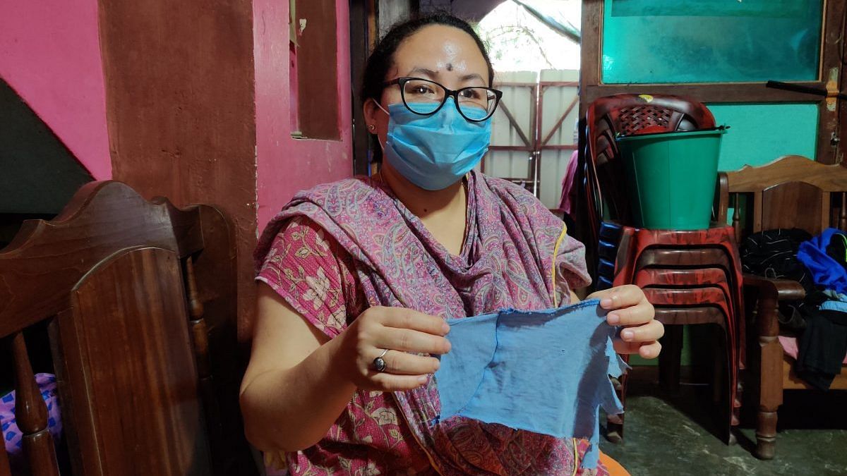 Kishorechandra Wangkhem’s wife Ranjita holds up a fragment of his T-shirt that she says was torn off when the police came to arrest him | Photo: Simrin Shirur/ThePrint
