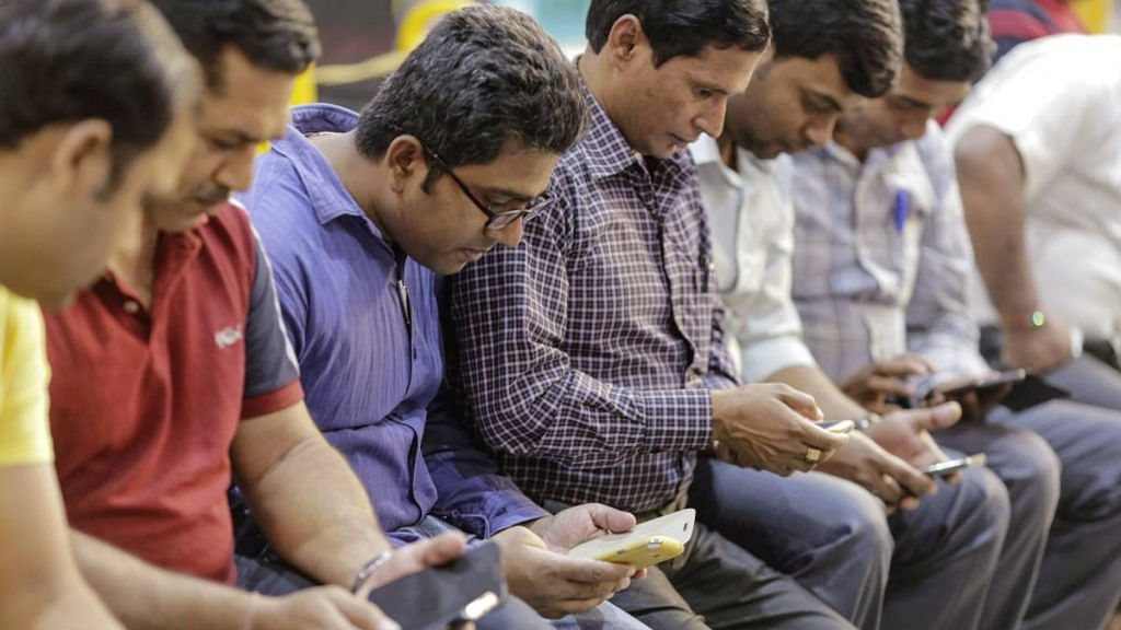 Representational image | People use smartphones at a railway station in Mumbai | Dhiraj Singh | Bloomberg