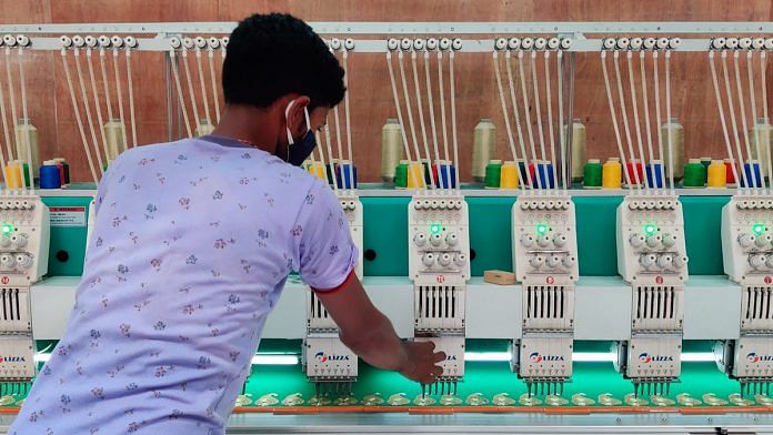 Rajiv Kumar, a worker at a sari unit in the West Champaran start-up zone, inspects a machine used to embroider the garment | Sajid Ali | ThePrint