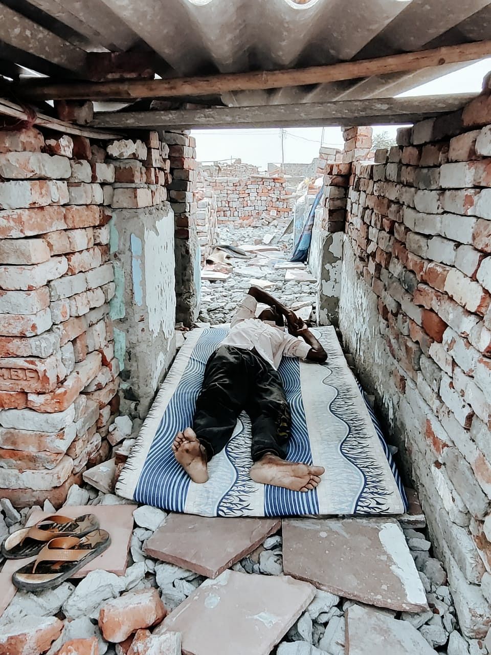 A resident sleeps in what remains of his house | Shubhangi Misra | ThePrint