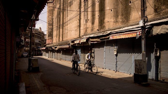Cyclists ride past closed stores in a deserted market area during lockdown restrictions in Agra, on 6 June 2021 | Bloomberg photo