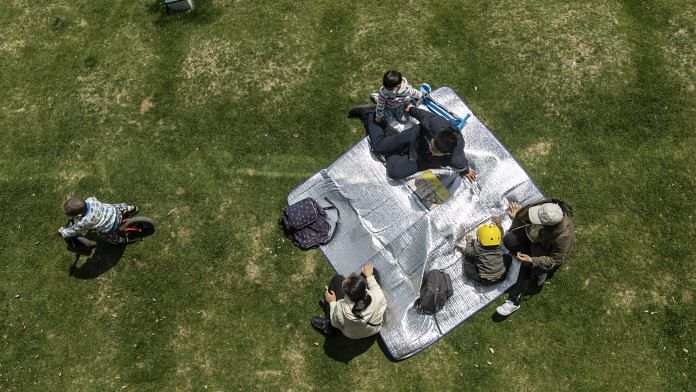 People picnic at a river-side park in Shanghai, China | Photo: Qilai Shen | Bloomberg