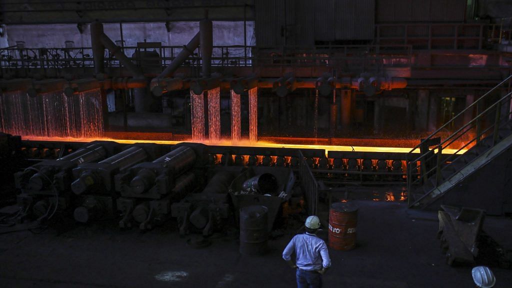 Water is sprayed on red hot steel slabs passing through a rolling machine inside the hot strip mill unit at the Steel Authority of India Ltd.| Photographer: Dhiraj Singh | Bloomberg