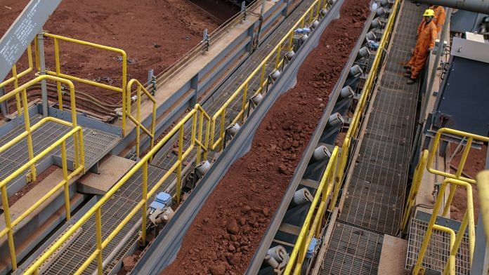 Workers monitor bauxite ore travelling a conveyor at the Vedanta Alumina Refinery in Lanjigarh district, Odisha