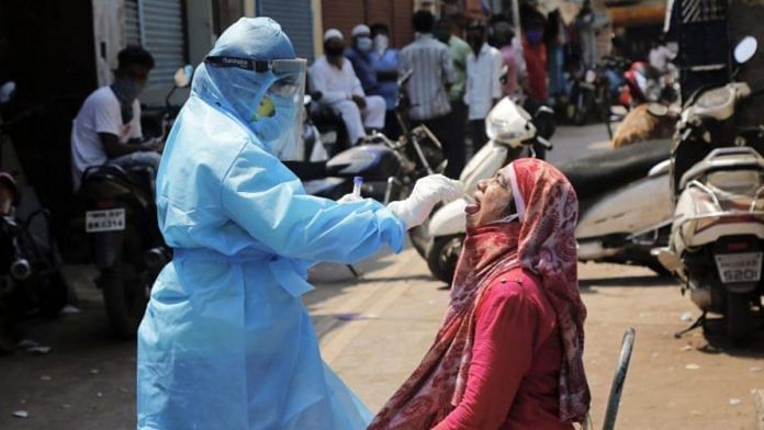 A medic collects swab from the mouth of a woman resident for Covid-19 test in a containment zone at Kurla, Mumbai Representational image | PTI