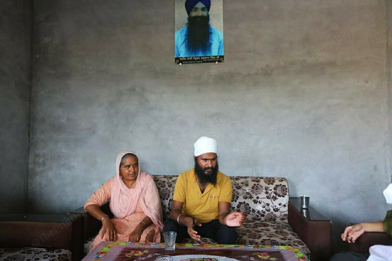 Prabdeep Singh with his mother Veerpal Kaur, under a photo of his father Krishan Singh | Praveen Jain | ThePrint