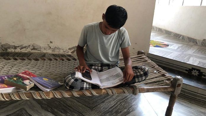 Rohit, a resident of Sehlang village in Mahendragarh district, reads a textbook at home | Jyoti Yadav | ThePrint