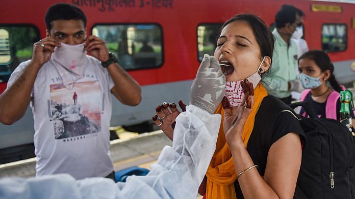 A BMC health worker collects a swab sample of a passenger for the Covid test, at a station in Mumbai, on 30 June 2021 | PTI