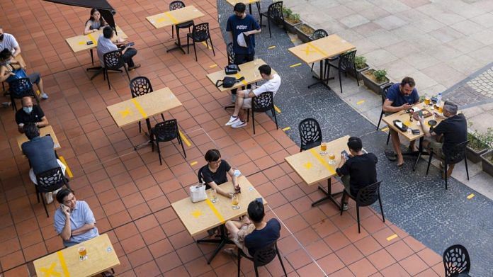 Customers sit at socially distanced tables outside a restaurant in Singapore, on 21 June 2021 | Bloomberg