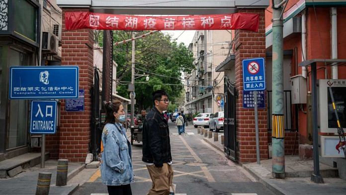 Pedestrians walk past a banner indicating a vaccination point at a residential compound in Beijing, China, in April 2021 | Yan Cong | Bloomberg