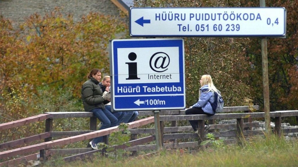 People sit close to a sign indicating internet availability, in Estonia's capital Tallinn