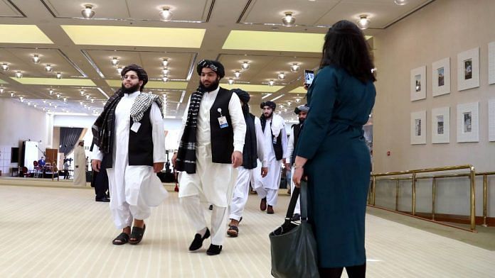 A woman watches as members of the Taliban delegation walk by ahead of an agreement signing between them and US officials in Doha, Qatar in February 2020 | ANI via Reuters