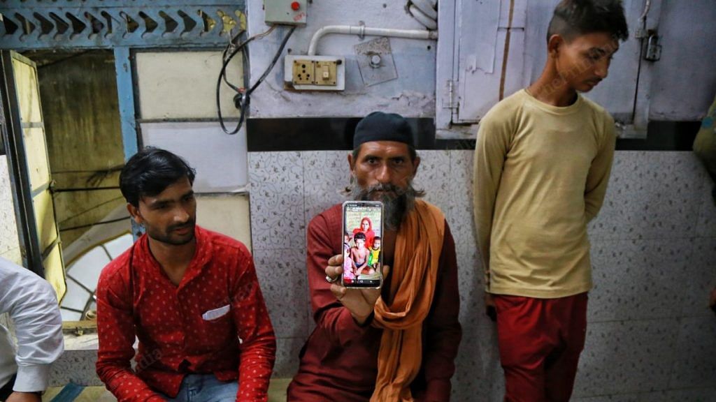 A relative holds up a photo of Tasleem Ali's family that lives in UP's Hardoi. A video of the bangle-seller being beaten up has gone viral. Ali is accused of molesting a girl, a charge his family denies | Manisha Mondal | ThePrint