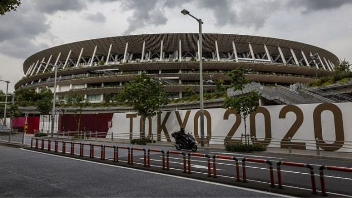 A man drives past the New National Stadium, the main stadium for the Tokyo Olympics in Tokyo | Photographer: Yuichi Yamazaki | Bloomberg