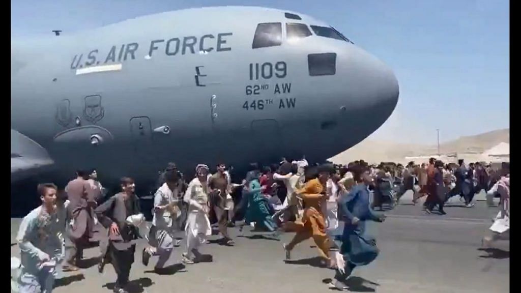 Afghanis scrambling to board the C-17 undercarriage of the US Air Force at the Kabul airport Monday | Twitter screengrab