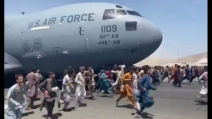 Afghanis scrambling to board the C-17 undercarriage of the US Air Force at the Kabul airport Monday | Twitter screengrab