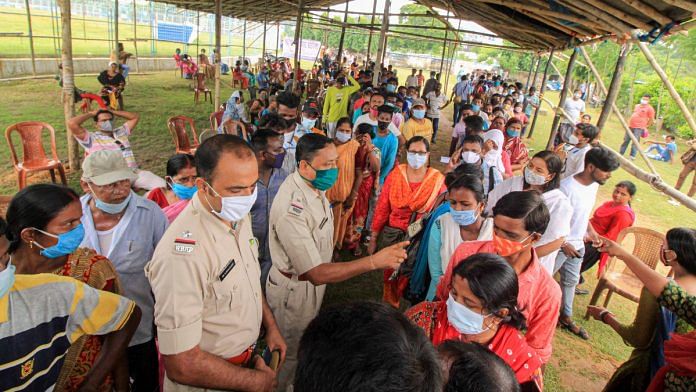 Police personnel instruct beneficiaries to maintain queues as they wait to receive Covid-19 vaccine during a mega vaccination drive camp organised at Bolpur Stadium in Birbhum district on 25 August 2021 | PTI