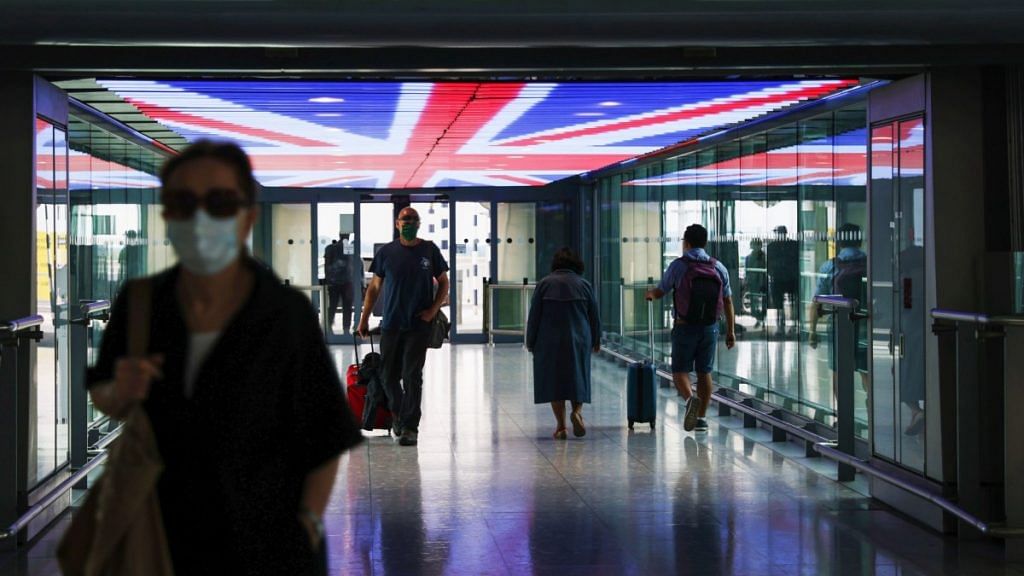 Travellers walk underneath a British Union Flag at Terminal 5, London Heathrow Airport Ltd. in London Photographer: Hollie Adams | Bloomberg