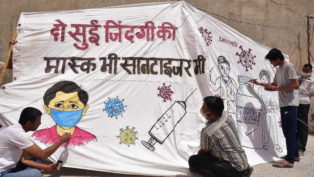People paint an awareness poster about getting vaccinated as well using sanitiser and mask in view of the Covid-19 pandemic, in Bikaner, Rajasthan in April 2021 | ANI