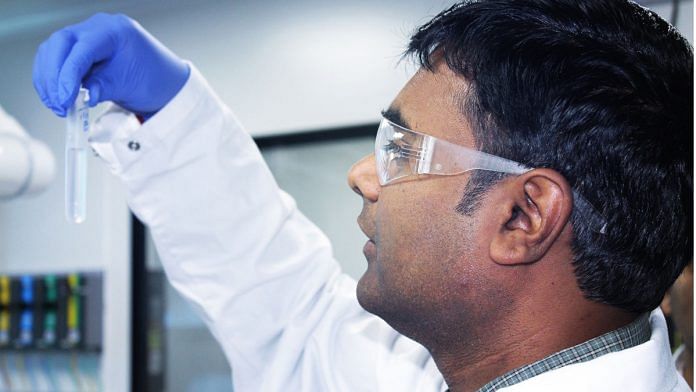 A lab worker at Biological E. Ltd's plant, holding a test tube vial | www.biologicale.com
