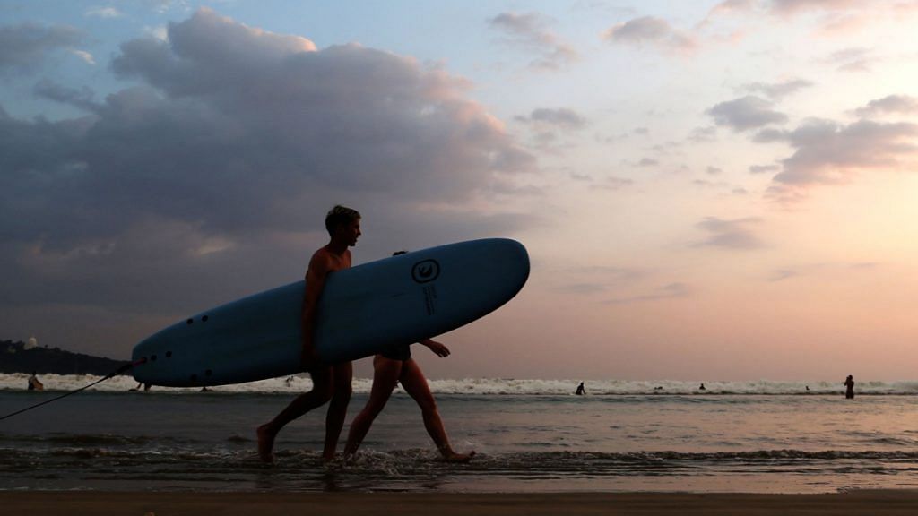 Tourists with a surfboard walk along Dewata Beach in Galle, Sri Lanka | Buddhika Weerasinghe | Bloomberg