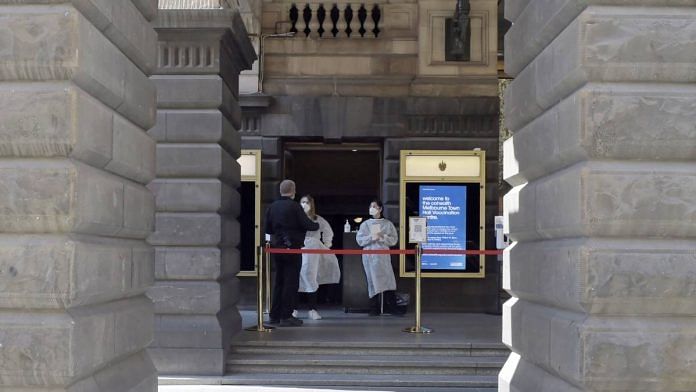 Medical workers in protective gear at the entrance to a vaccination hub in the Town Hall in Melbourne, Australia, earlier this month. | Bloomberg