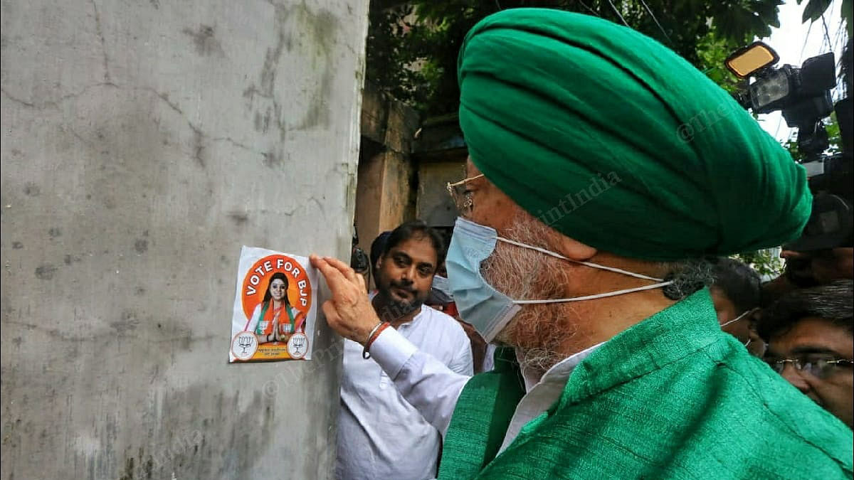 Union Minister Hardeep Singh Puri putting up a poster of Priyanka Tibrewal, the BJP candidate, in Bhabanipur | Praveen Jain, ThePrint