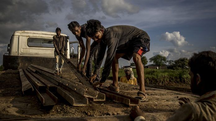 Workers unload construction materials from a truck at the site of a flyover in Guna, Madhya Pradesh | Representational work | Photo: Anindito Mukherjee | Bloomberg