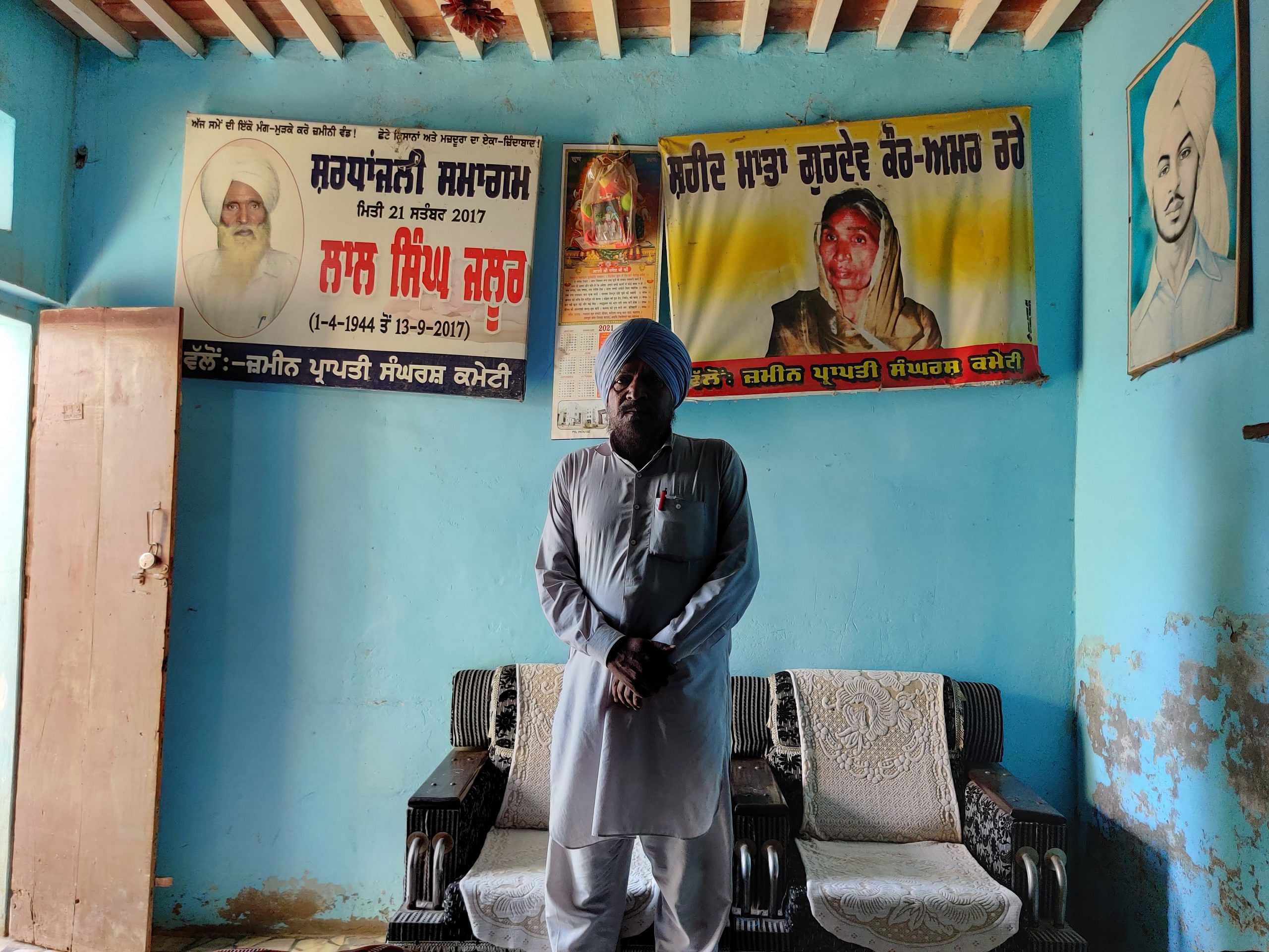 पंजाब के संगरूर जिले के झालूर गांव में गुरदेव कौर का बेटा बलबीर सिंह, जिसका पोस्टर (पीछे-दाएं) भगत सिंह के फ्रेम के बगल में लटका हुआ है। | उर्जिता भारद्वाज | दिप्रिंट 