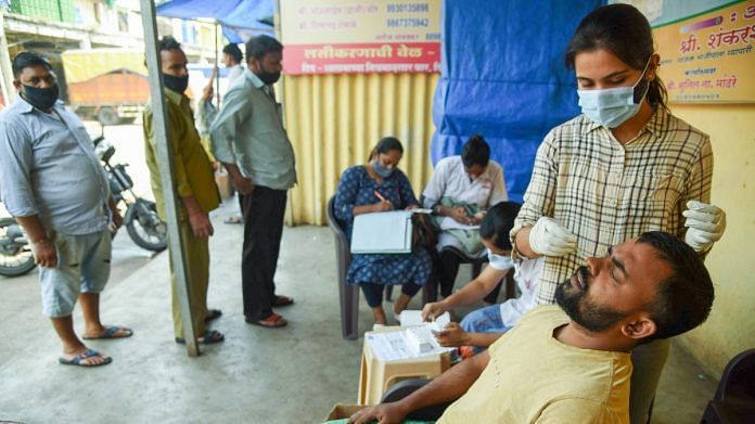 A medic takes a swab sample of a man for the Covid-19 test, at APMC vegetable market in Navi Mumbai, on 16 October 2021 | PTI