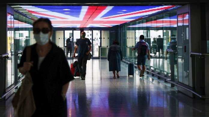 Travellers walk underneath a British Union Flag at Terminal 5, London Heathrow Airport Ltd. in London, UK | Photographer: Hollie Adams | Bloomberg