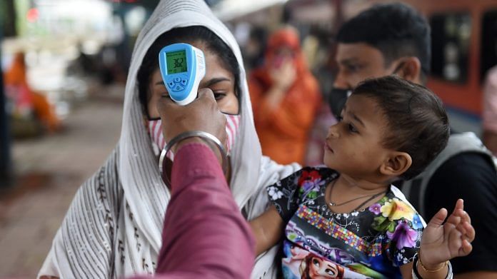 A health worker checks the body temperature of a traveller as a precaution against the coronavirus before allowing her to proceed at a railway station, in Mumbai, on 30 September 2021 | PTI