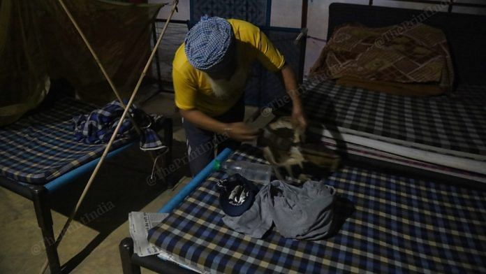 A fellow protester wraps up Gurpreet Singh's belongings after his alleged suicide at Singhu border Wednesday | Manisha Mondal | ThePrint