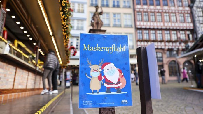 A sign reminds visitors to wear face masks while visiting a Christmas market in Frankfurt, Germany, on 22 November 2021 | Photo: Alex Kraus | Bloomberg