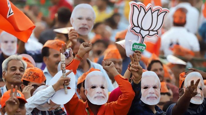 BJP supporters wear masks in the likeness of PM Narendra Modi during a rally at Ramleela Ground in New Delhi | Photographer: Anindito Mukherjee | Bloomberg