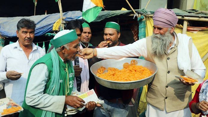 Bharatiya Kisan Union (BKU) supporters offer 'jalebis' at Ghazipur border as part of celebration after Prime Minister Narendra Modi announced the withdrawal of three farm laws. | ANI