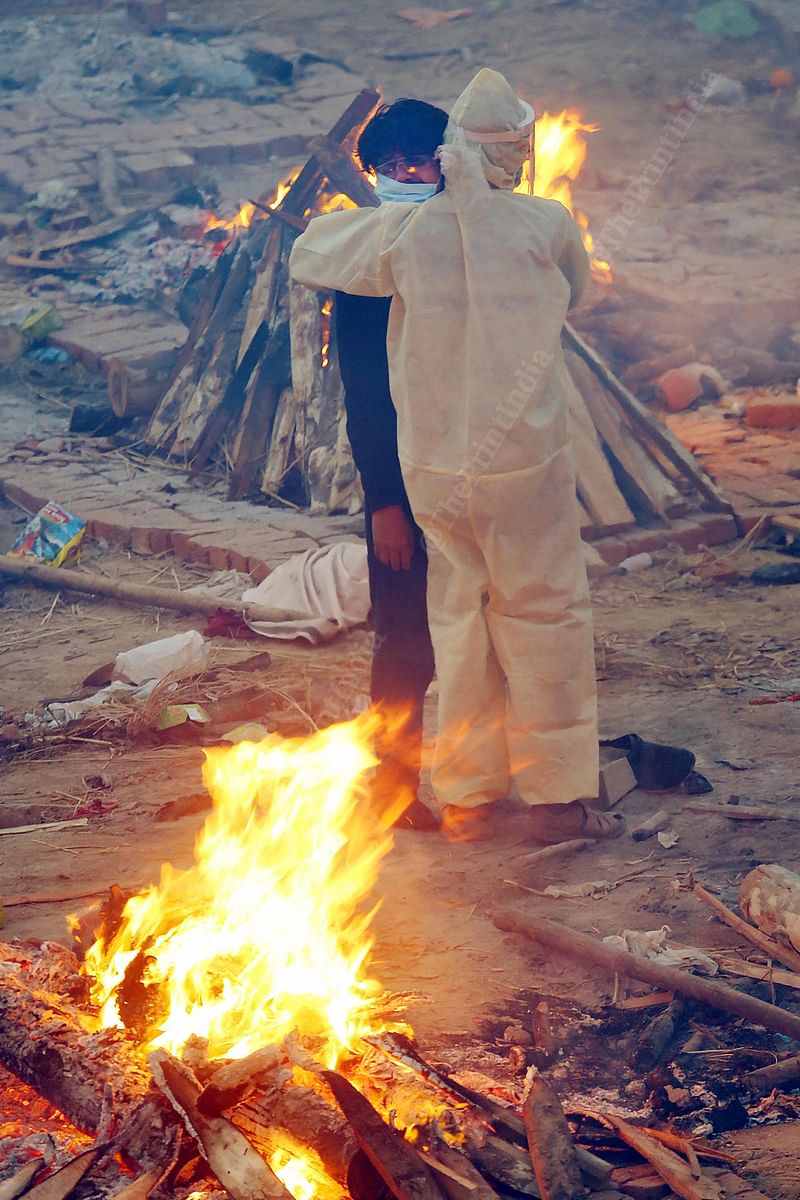 Family members stand between burning pyres at the Seemapuri crematorium | Praveen Jain | ThePrint