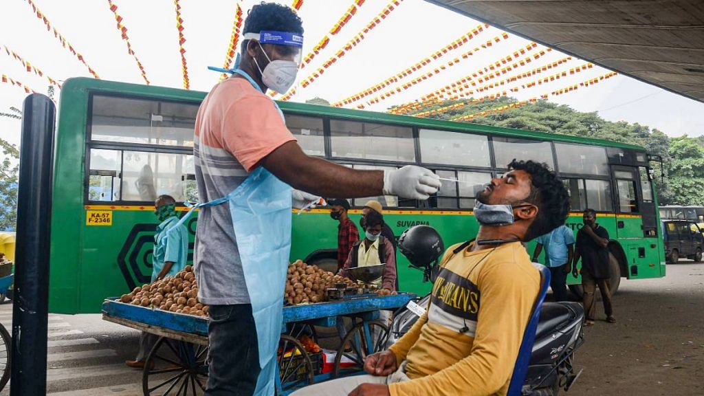 A health worker collects a swab sample from a commuter in Bengaluru on 2 December | PTI