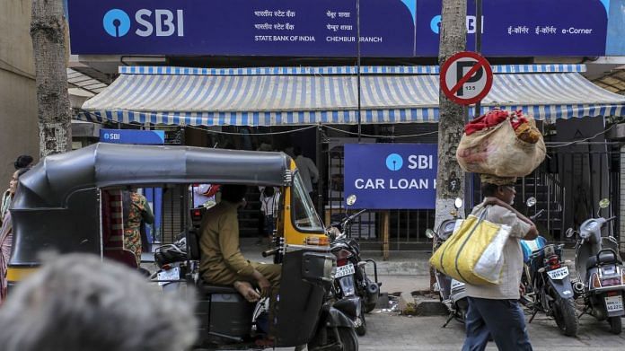 Pedestrians and an auto-rickshaw pass a State Bank of India (SBI) branch in Mumbai | Bloomberg