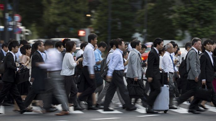 Commuters cross a road in the central business district of Tokyo, Japan | Representational image | Bloomberg