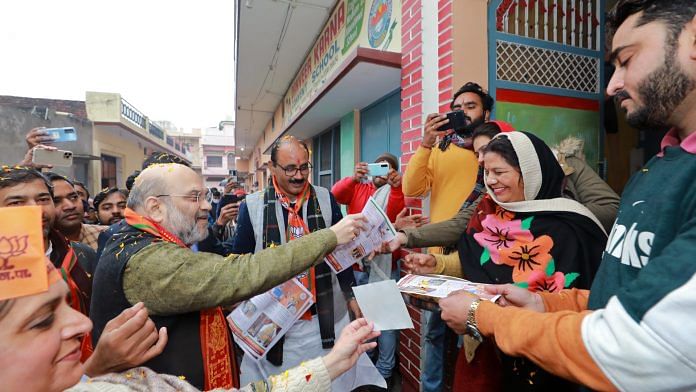 Amit Shah distributes a pamphlet during a door-to-door campaign in Kairana, on 22 January 2022 | ANI Photo