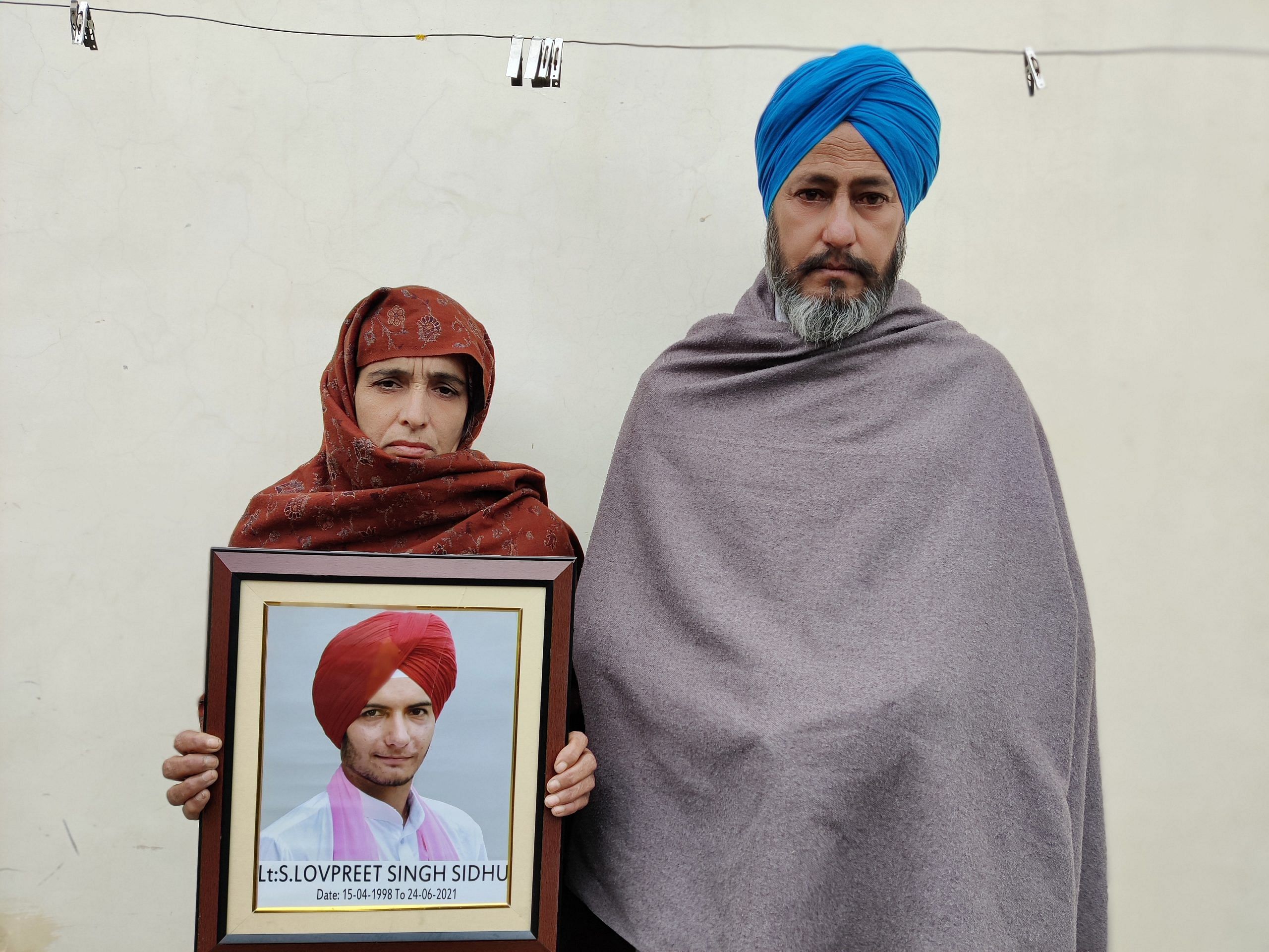 Parents of Lakhwinder Singh 'Ladi' stand with his photograph at their house. Ladi drank fertilizer and killed himself after he was abandoned by his wife | Shubhangi Misra | ThePrint 
