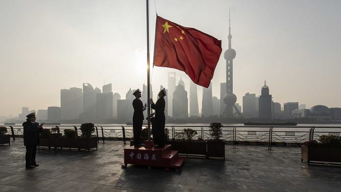 A Chinese flag being raised in the Lujiazui Financial District of Shanghai | Photo: Qilai Shen | Bloomberg