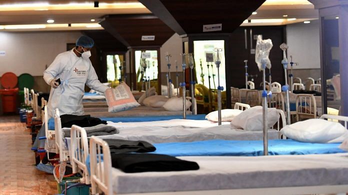 A healthcare worker prepares beds inside a temporarily converted isolation ward for Covid patients in Shehnai Banquet Hall, on 23 January 2022 | ANI photo