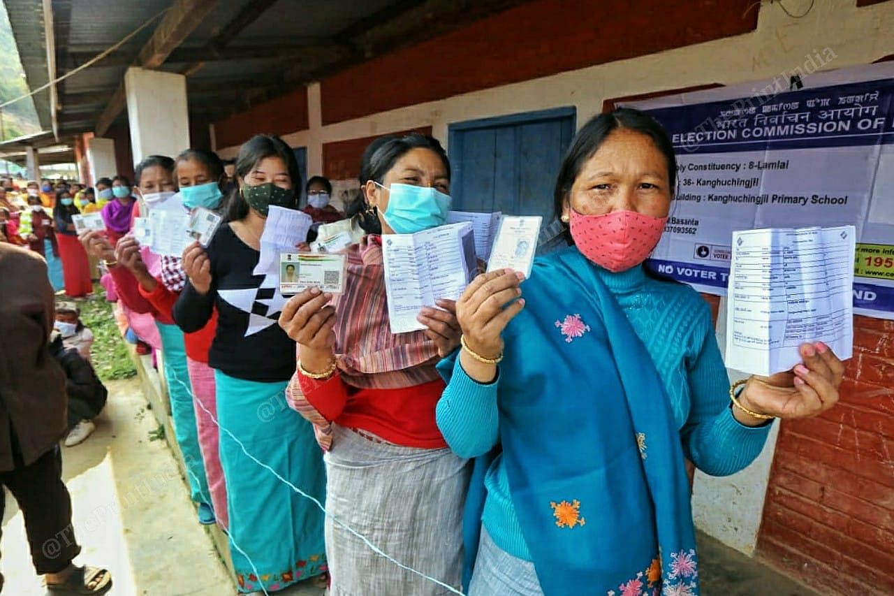 People hold up their identification documents as they wait to cast their votes at Lamlai, Manipur | Praveen Jain | ThePrint