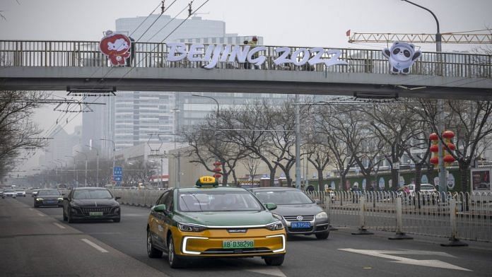 Vehicles travel past a sign for the Beijing 2022 Winter Olympic and Paralympic Games on a walkway in Beijing, on 24 January 2022 | Bloomberg