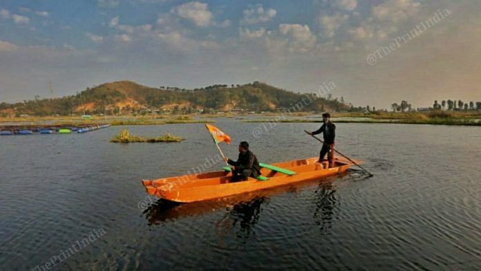 A BJP supporter carries the party's flag over the Loktak lake | Photo: Praveen Jain | ThePrint