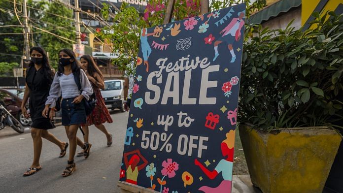 Pedestrians pass a sale sign outside a clothing store in Hauz Khas Village in New Delhi